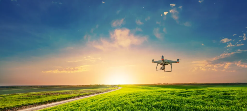 Drone flying over a green field at sunset